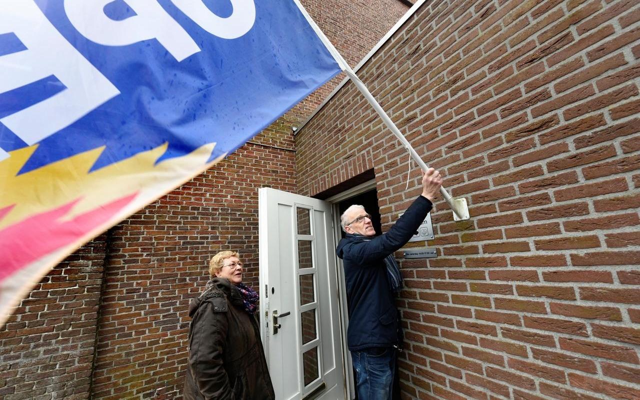 René Klaassen en gastvrouw Lies Kruiper hangen de vlag uit bij Inloophuis ’t Centrum in Drachten. Morgen vieren ze het tienjarig bestaan van het inloophuis in de Grote Kerk.