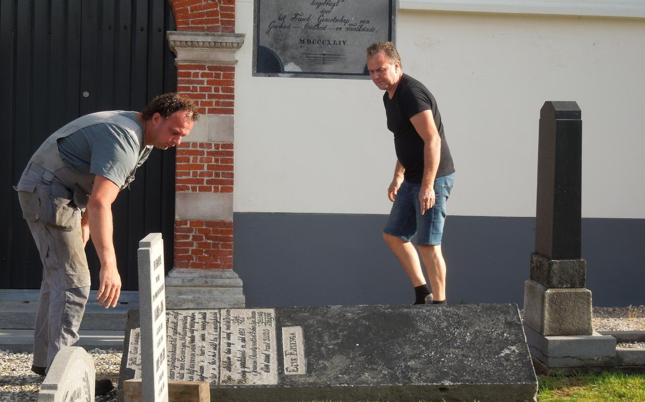 Steenhouwer Ben Seldenrijk (rechts) en een medewerker lichten de grafsteen van Eise Eisinga.
