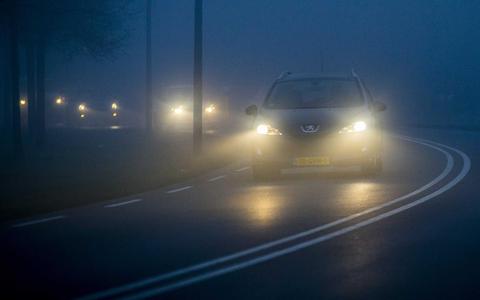 Een auto rijdt door de mist.