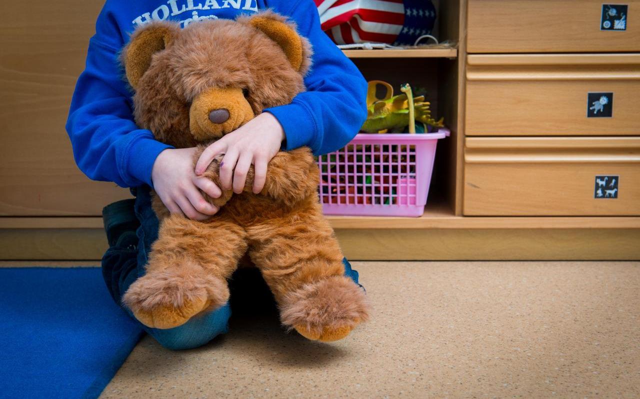 Een jongen met een knuffelbeer in een speelkamer van een jeugdhulpverleningscentrum.