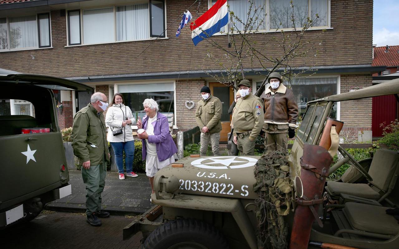 Bauke Sienema (links) deelt soep uit aan Richje Mud-Dijkstra in Franeker. Links staat haar kleindochter Wendy Tinga. Rechts de bestuurders van de andere legervoertuigen.