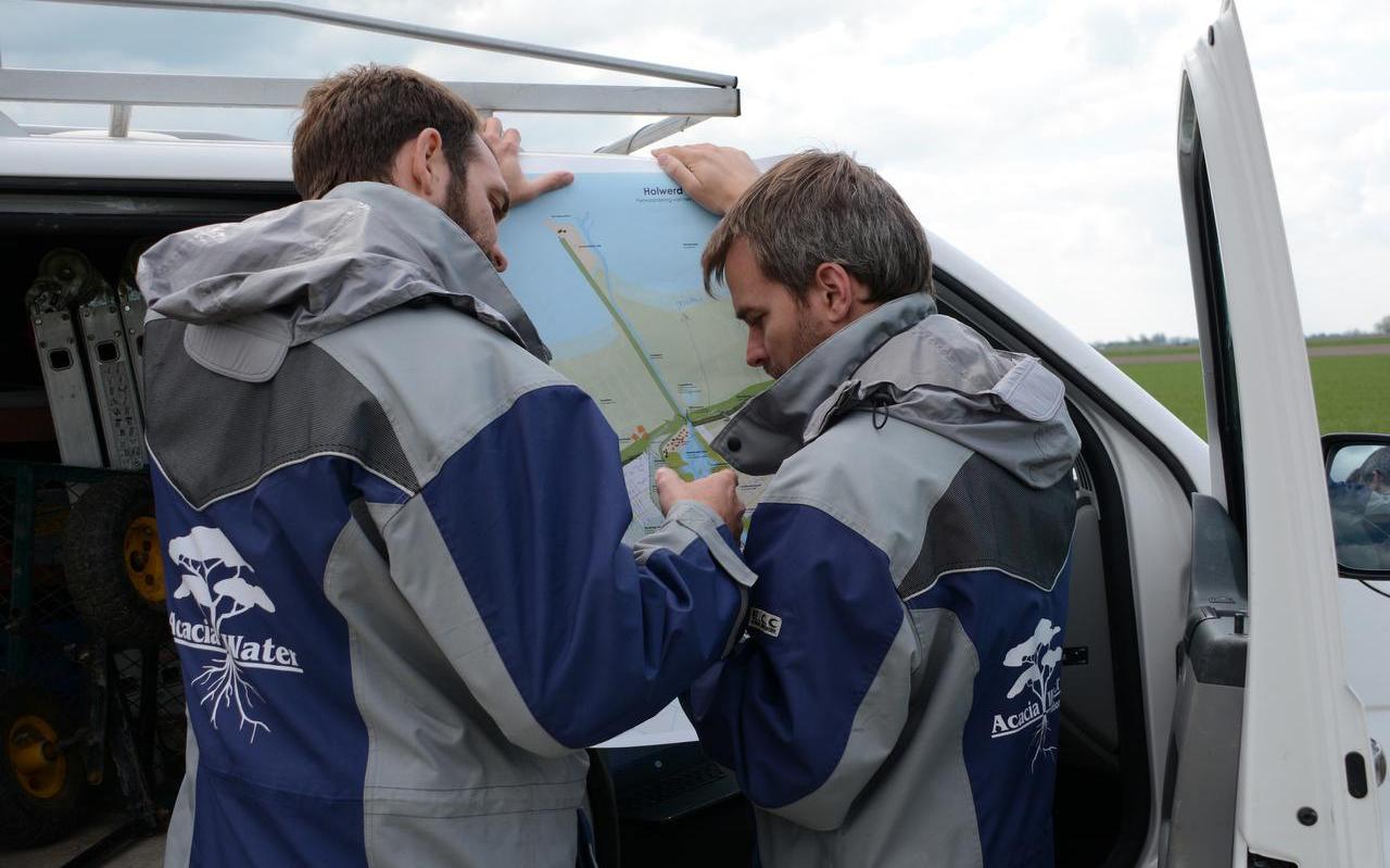 Twee medewerkers van Acacia Water bekijken de kaart voor Holwerd aan Zee. Ze zijn deze week gestart met hydrologisch onderzoek om de effecten van het getijdenmeer op de omgeving te meten.
