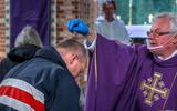 Pastoor Van der Weide strooit op Aswoensdag as over een hoofd in de Sint-Martinuskerk in Sneek.