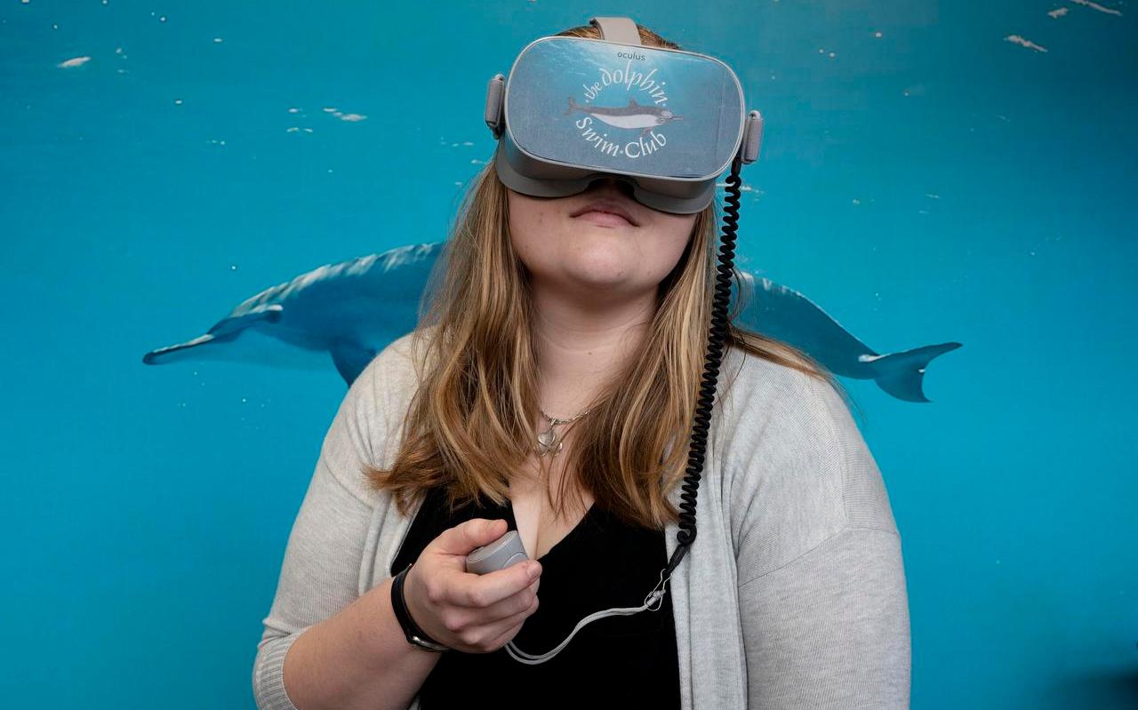 Tess Smit waant zich met VR-bril tussen de zwemmende dolfijnen.