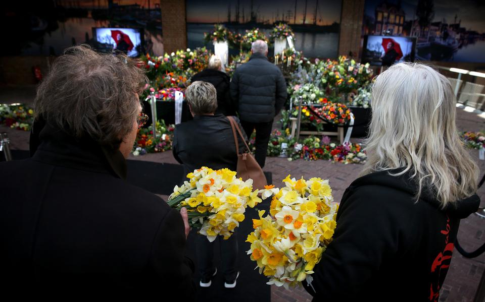 Bezoekers geven massaal gehoor aan de oproep om kleurige bloemen mee te nemen naar het afscheid van Piet Paulusma. 