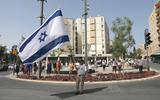 Een man staat tijdens twee minuten stilte met een grote Israëlische vlag op een rotonde in Jeruzalem.