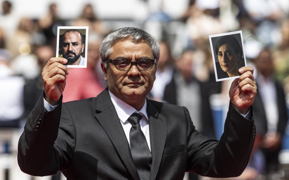 De Iraanse regisseur Mohammad Rasoulof houdt op de rode loper in Cannes foto's omhoog waarop de acteurs Soheila Golestani en Missagh Zareh te zien zijn. Zij konden Iran niet verlaten.