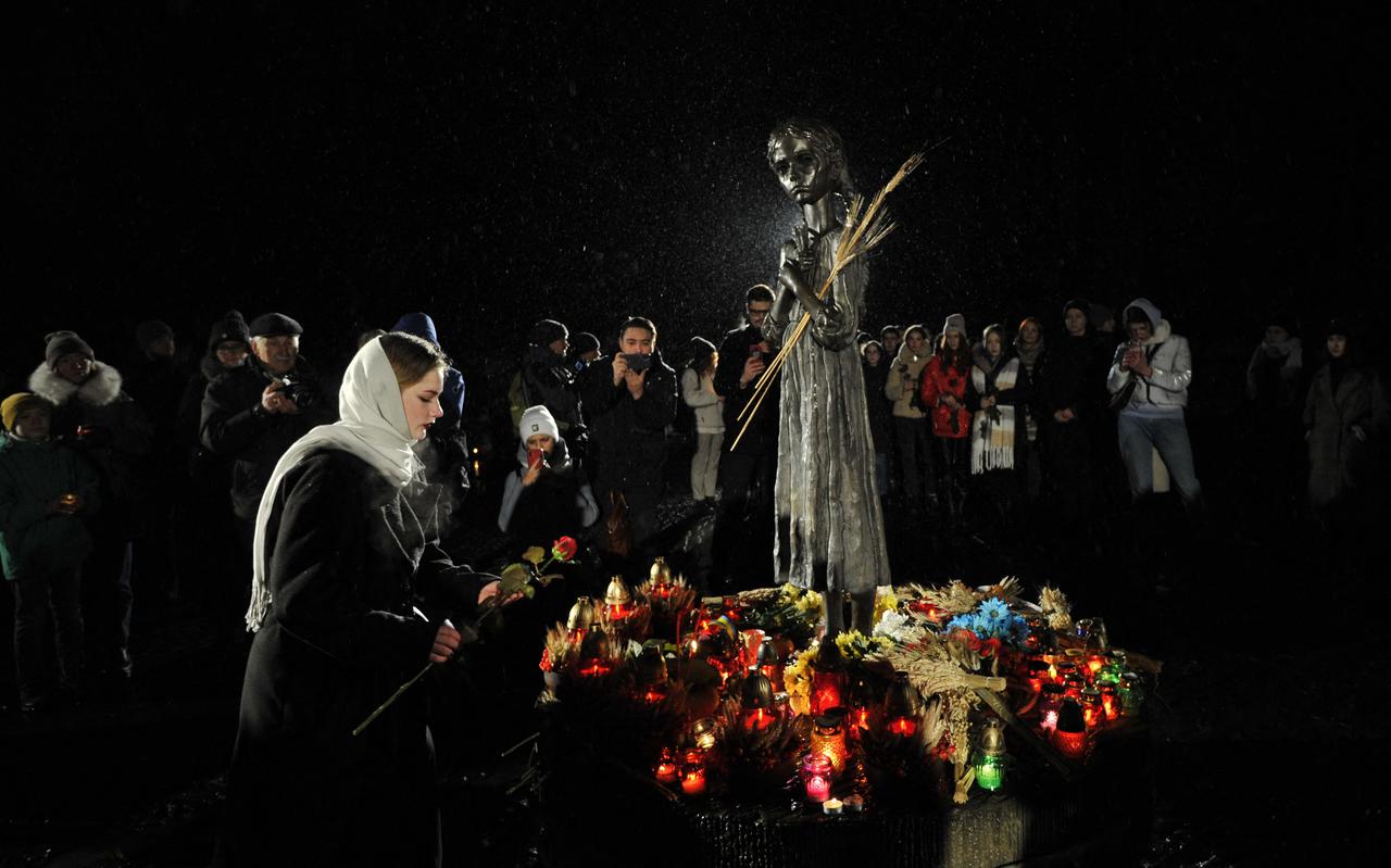 Een Oekraïense legt bloemen bij het monument ter nagedachtenis aan de Holodomor, op 26 november 2022.