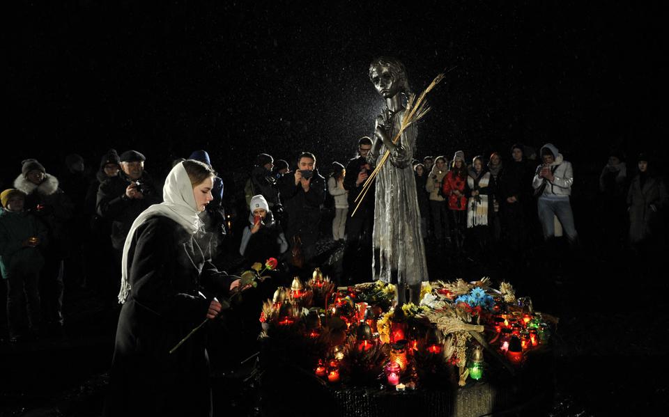 Een Oekraïense legt bloemen bij het monument ter nagedachtenis aan de Holodomor, op 26 november 2022. 