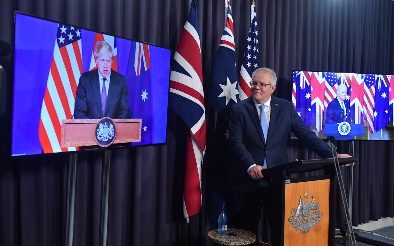 De Australische premier Scott Morrison kondigt het AUKUS-bondgenootschap aan, geflankeerd door de Britse premier Boris Johnson (l) en de Amerikaanse president Joe Biden op beeldschermen. 