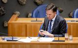 Premier Mark Rutte zit op zijn telefoon in de Tweede Kamer tijdens het debat over de sms-berichten van de premier.