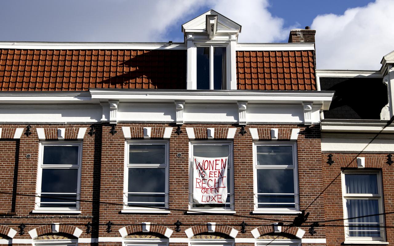 Een poster voor het raam van een woning met de tekst: Wonen is een recht, geen luxe. Een poster voor het raam van een woning met de tekst: Wonen is een recht, geen luxe.