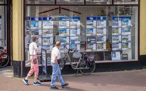 Woningzoekenden of geïnteresseerden staan te kijken naar welke huizen of appartementen nog te koop staan bij een makelaar en taxateur in de binnenstad van Delft. 