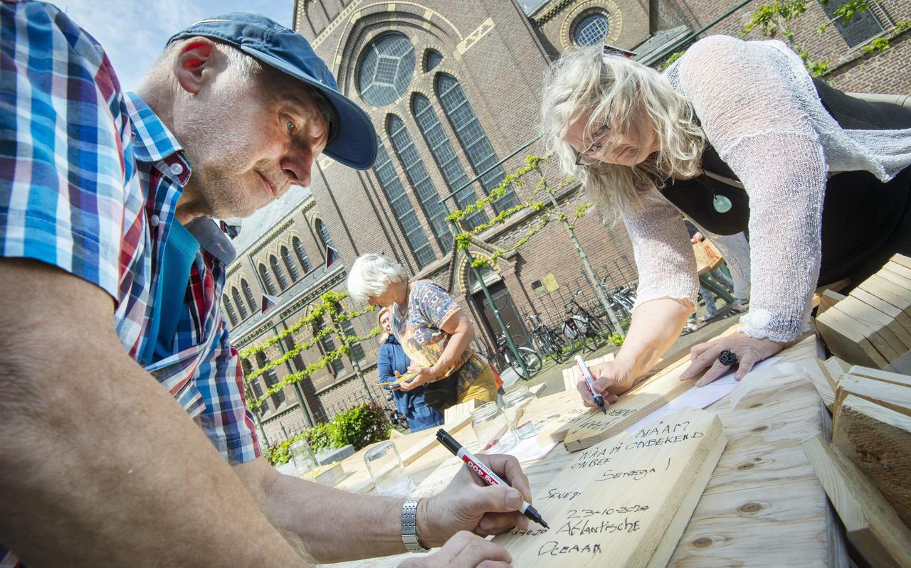 Jappy Talma en Wietske Wiersma zijn op de Bargemerk in Dokkum bezig met de houten gedenktekens voor omgekomen vluchtelingen.