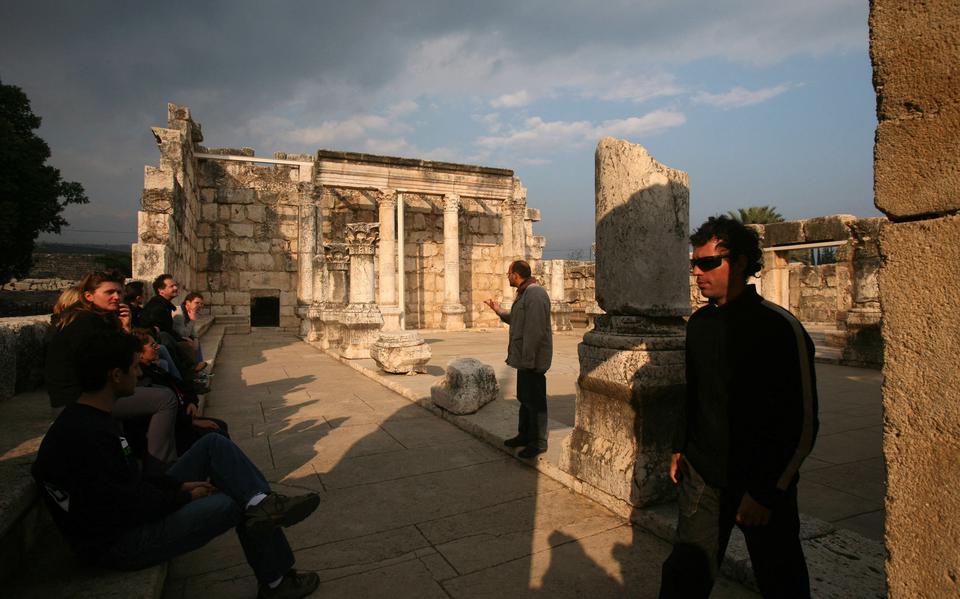 Touristen bezoeken de ruïnes van een synagoge in Kafarnaüm. 