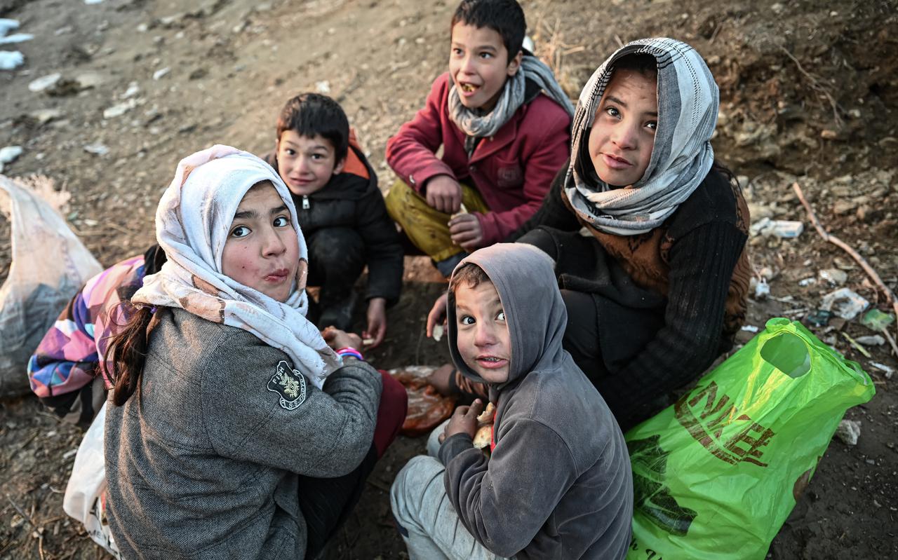 Afghaanse kinderen eten samen een brood op. Volgens de Verenigde Naties hebben bijna 23 miljoen mensen, circa 55 procent van de bevolking, te maken met extreme honger. 