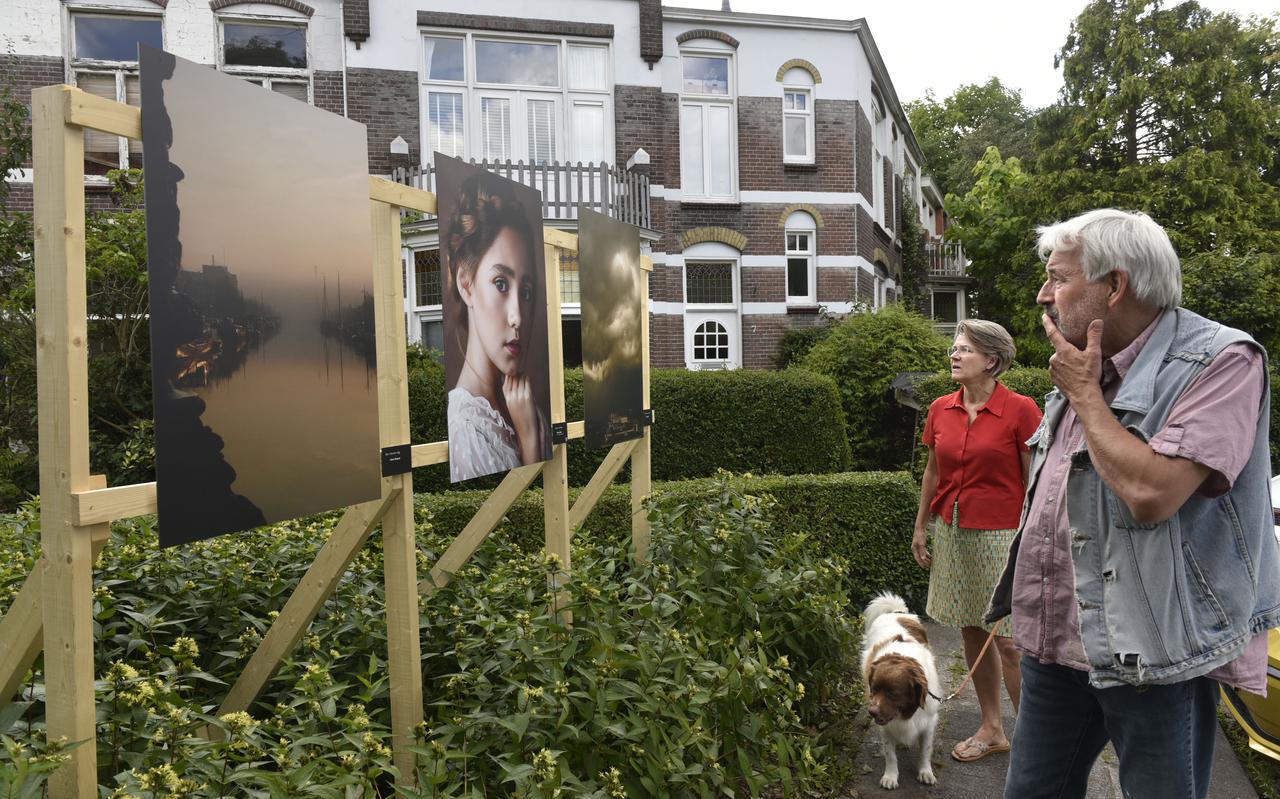 Voorbijgangers bekijken in de Emmastraat in Leeuwarden foto's van Hans Stapel (links en rechts). De foto in het midden is gemaakt door Sita Koning. 