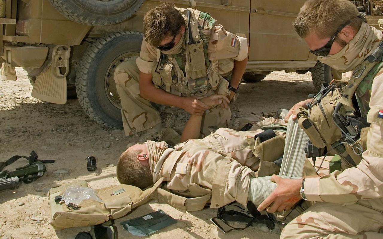 Archieffoto van special forces die in woestijnachtig gebied oefenen in het verzorgen van gewonden waarbij daadwerkelijk een infuus wordt ingebracht.  