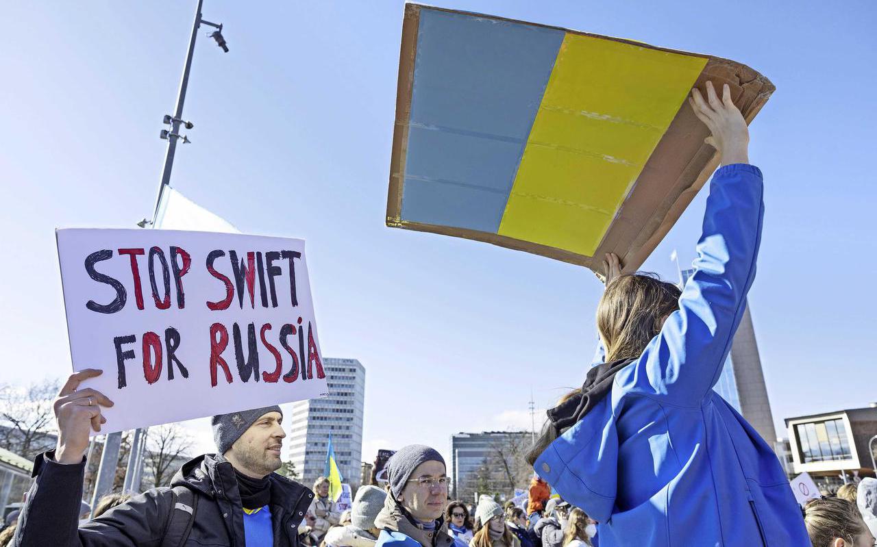 Genève - Een demonstrant houdt een bord omhoog waarop staat 'Stop Swift for Russia' tijdens een protest tegen de Russische inval in Oekraïne. EPA.