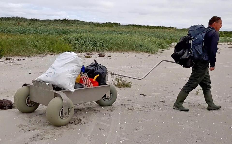 Een vrijwilliger ruimt voor Rijkswaterstaat afval op aan de stranden bij de Waddenzee. 