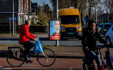 Voorbijgangers kijken naar een verkiezingsbord van de PvdA in Heerenveen. 