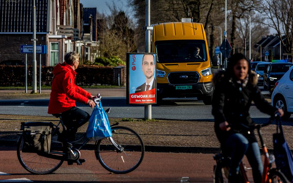 Voorbijgangers kijken naar een verkiezingsbord van de PvdA in Heerenveen. 