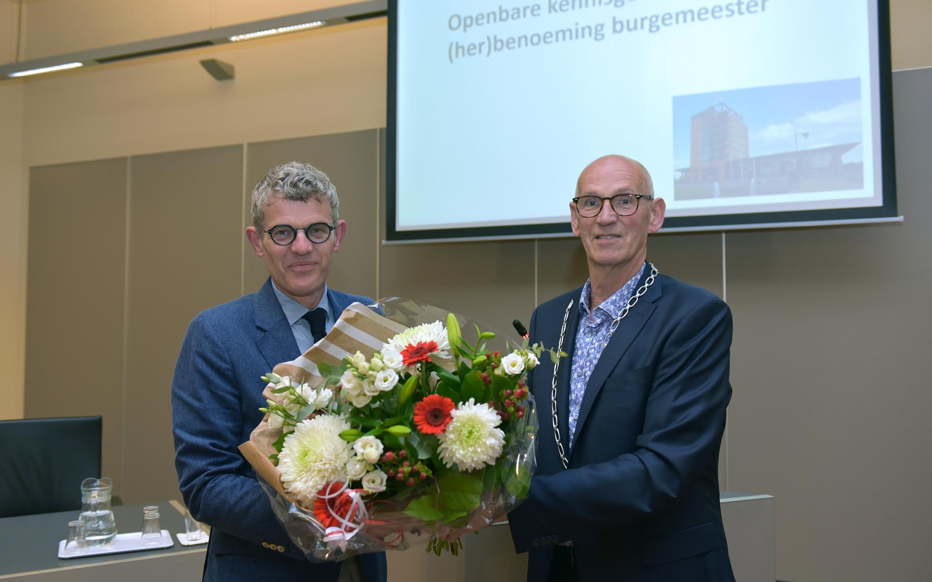 Burgemeester André van de Nadort (l) krijgt bloemen van Ton Mulder.