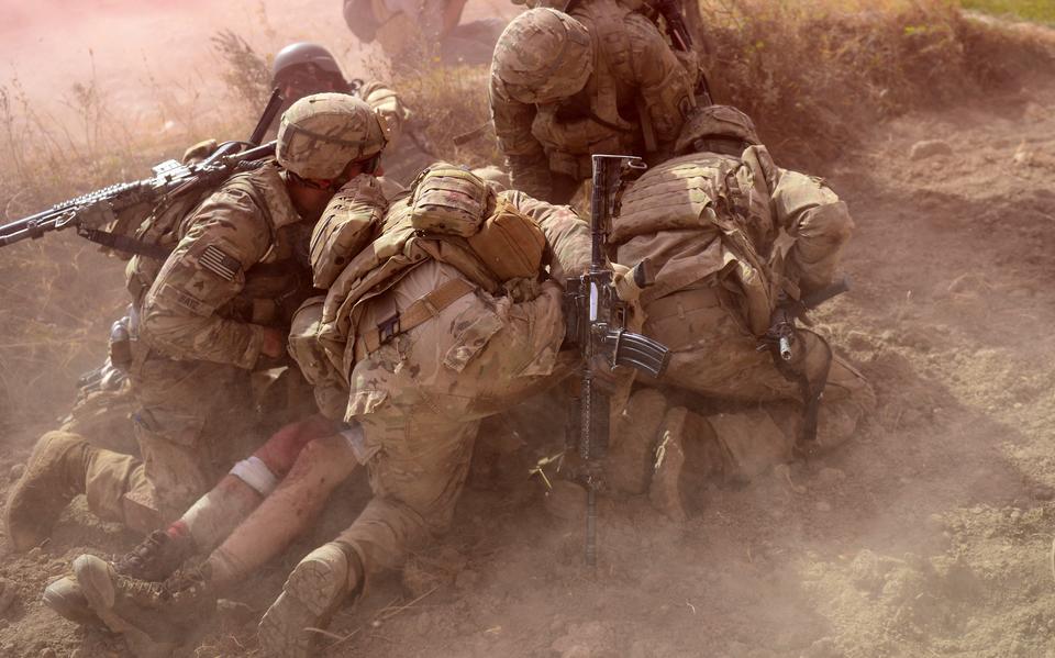 Amerikaanse soldaten beschermen een gewonde kameraad tegen opwaaiend zand van een landende reddingshelikopter, oktober 2012.