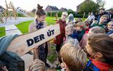 Buurtkinderen in Lemmer onthullen bord met de naam van de nieuwe speeltuin. In de rode jas initiatiefnemer Corina Hoekstra.