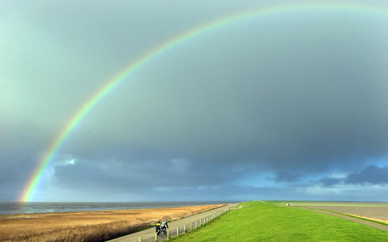 Regenboog boven fietsers op de Zeedijk nabij Westhoek. Regenboog boven fietsers op de Zeedijk nabij Westhoek.