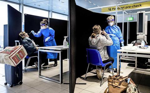 Reizigers uit Zuid-Afrika laten zich bij aankomst op de luchthaven testen op het coronavirus.