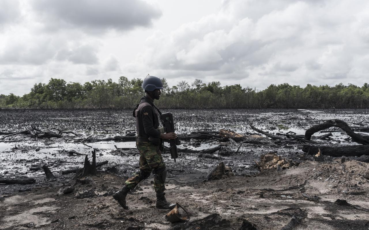 Een Nigeriaanse militair die behoort bij een opsporingseenheid die illegale olieraffinaderijen oprolt, loopt door een door zware olievervuiling aangetast magrove-bos in de Nigerdelta. 