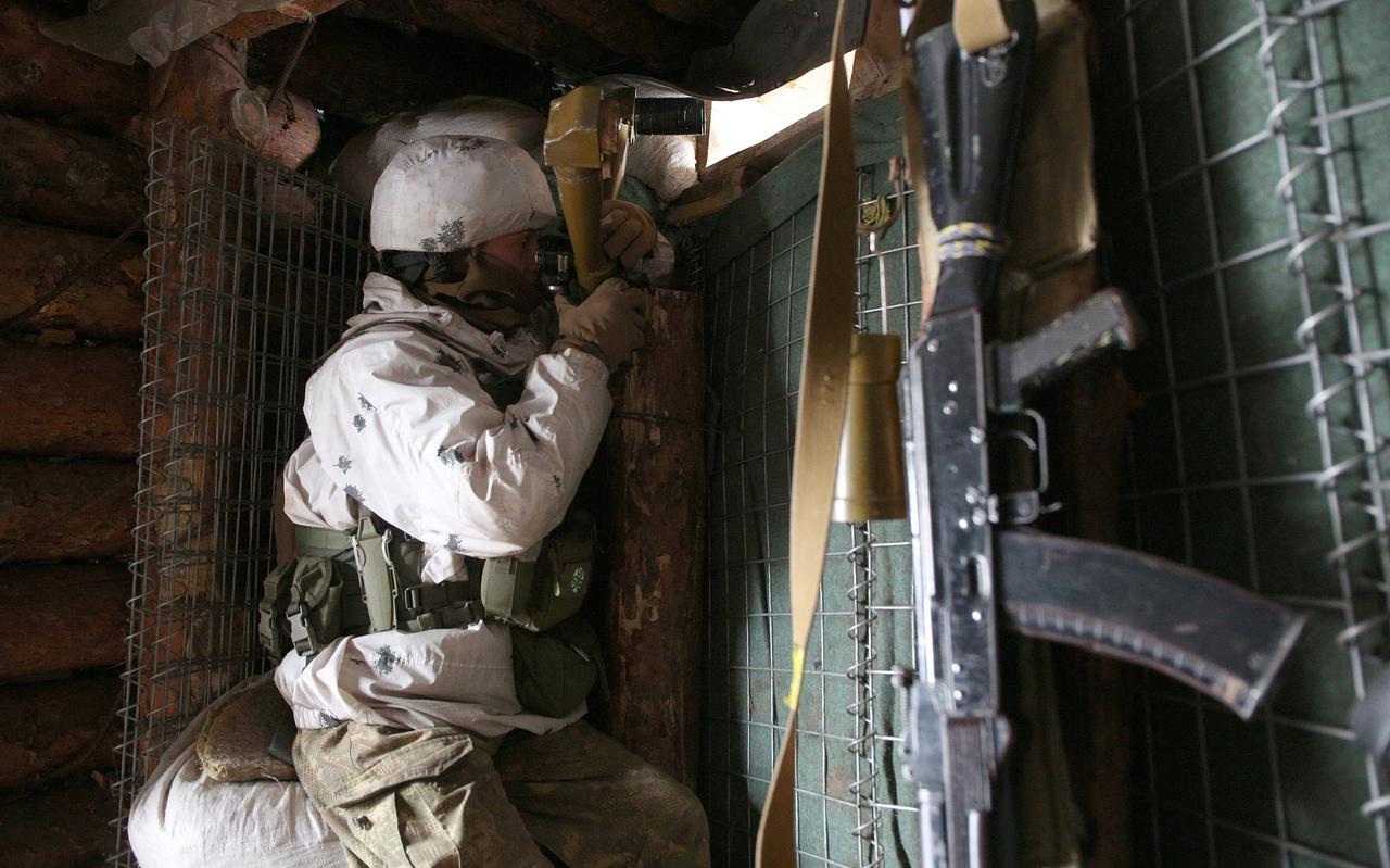 Een Oekraïense militair bekijkt vanuit een loopgraaf de frontlijn in Oost-Oekraïne waar pro-Russische rebellen actief zijn. 