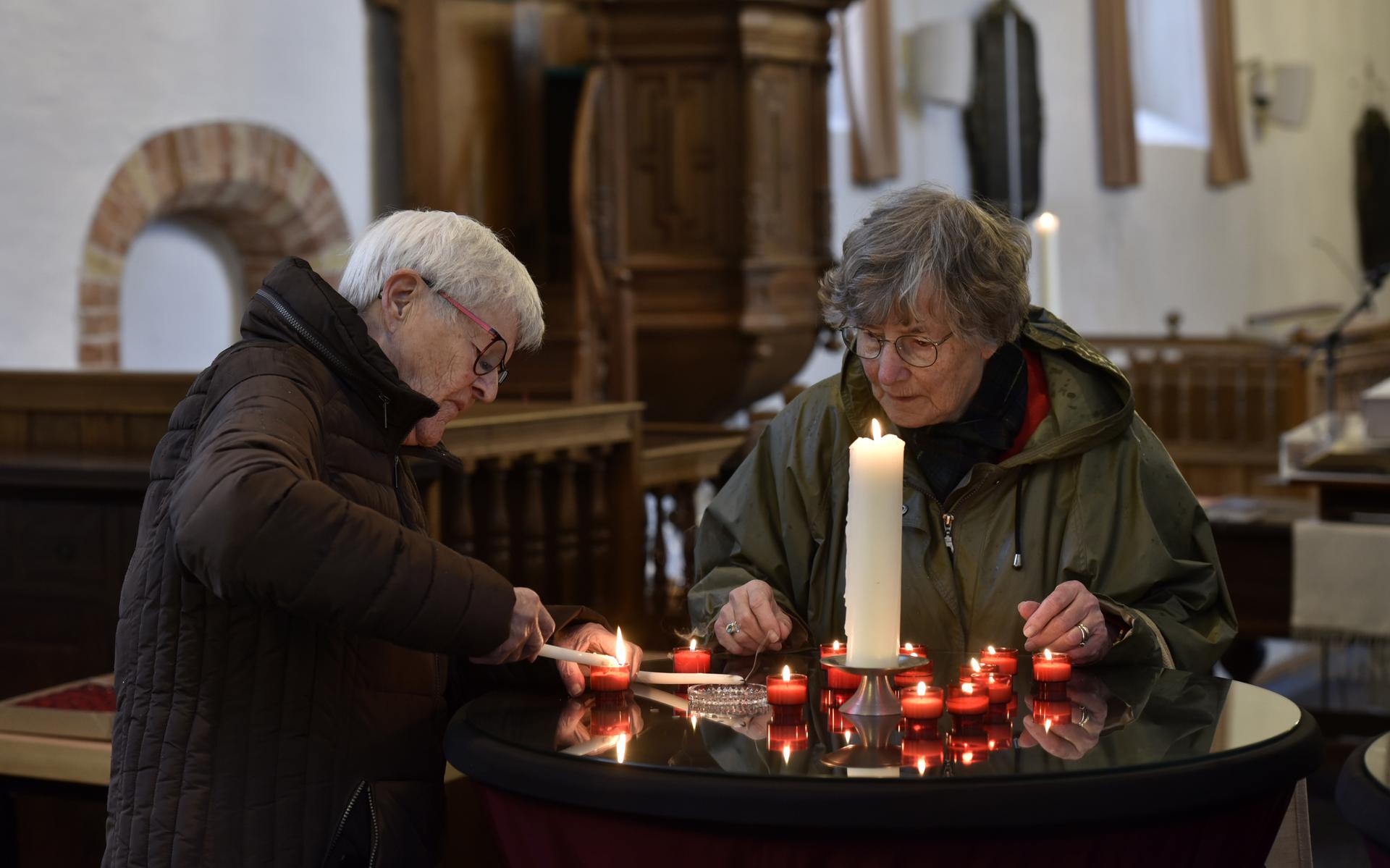 Hennie Groen-Pees (l) en Thea Slagman- Diekstra steken kaarsjes aan tijdens Allerzielen in de Sint-Vituskerk in Stiens. 
