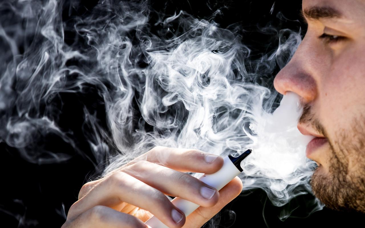 Een jonge man rookt een vaper, oftewel een e-sigaret.