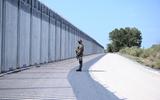 Een soldaat staat voor een stalen hek gebouwd langs de Evrosrivier op de Grieks-Turkse grens. 