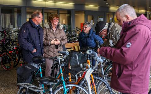 Stoffel Baas en Rennie Bloemsma (links) reiken een fiets uit aan een Oekraïense vluchteling (rechts).