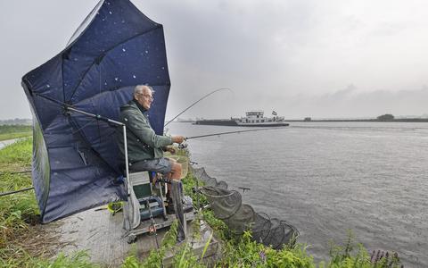 Tonny de Jong zit in de stromende regen te vissen langs de oevers van de Wide Ie tussen Suwâld en Burgum. 