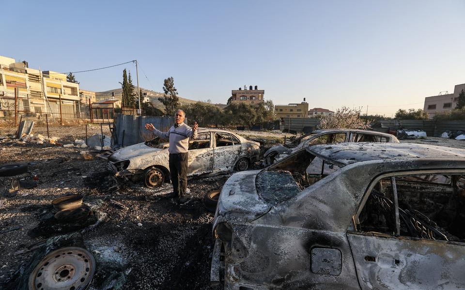 Een Palestijnse man bekijkt in brand gestoken auto's die naar een sloperij bij Huwara zijn gebracht. 