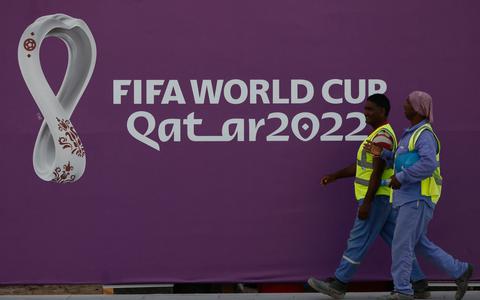 Arbeiders lopen langs een banner van FIFA World Cup in Doha.