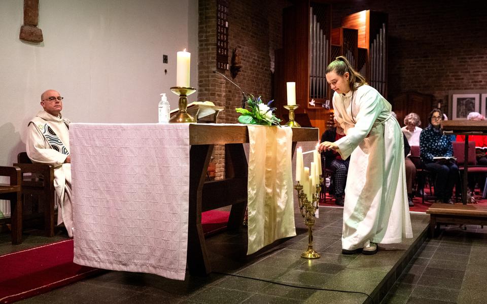 Tessa Grijze ontsteekt kaarsen tijdens het noemen van de namen van overledenen, bij de gecombineerde viering van Allerheiligen en Allerzielenviering in de Sint Pauluskerk in Gorredijk. Achter het altaar pastoor Koos Tolboom. 