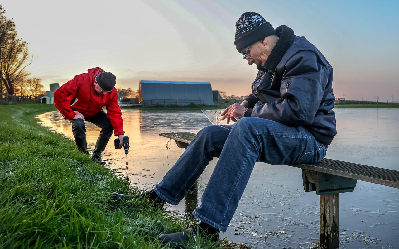 Gerard Postma (rood) boort en de man die de boor de afgelopen 40 jaar heeft gehanteerd, Sipke Blumers, meet het ijs