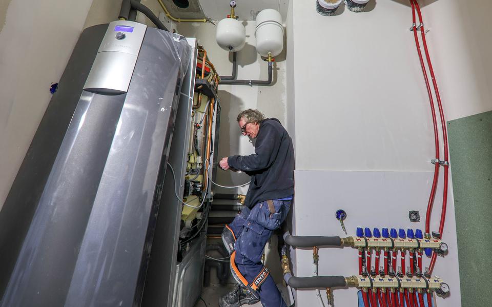 Een elektricien installeert een warmtepomp in een nieuw appartementencomplex in Oosthem. 