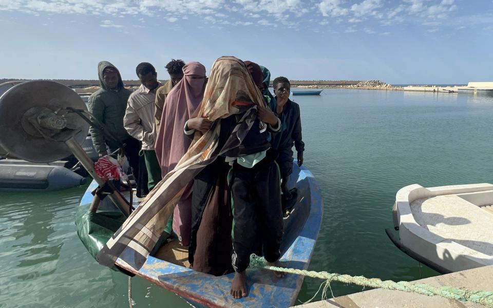 Geredde migranten in een klein bootje bij de kust van Libië.
