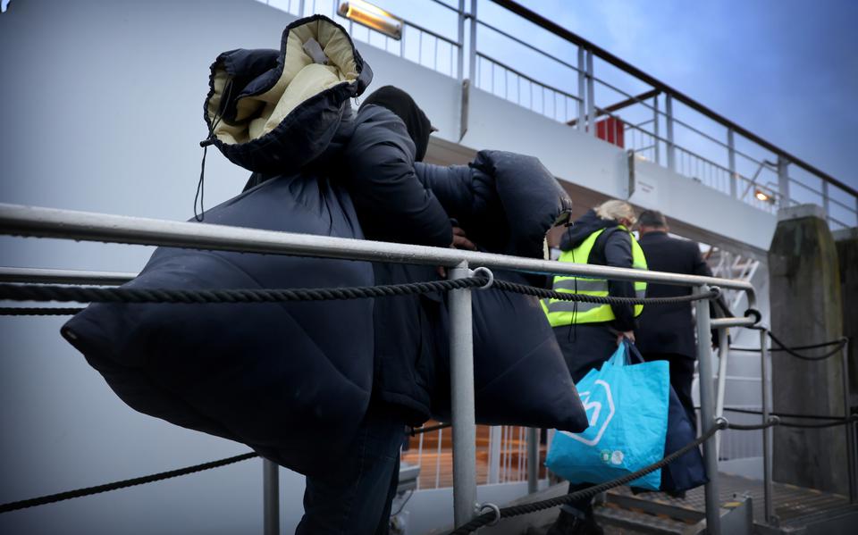 Asielzoekers komen aan in Harlingen, waar een cruiseschip wordt gebruikt als crisisnoodopvang.