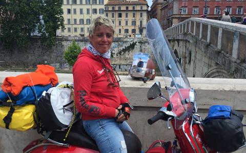 Janneke Abma-Horjus op de rode Vespa bij de brug in Rome waar de belofte deed aan Johan.
