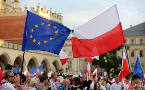 De Poolse en EU-vlag aan elkaar geknoopt bij een protest in Krakau. 