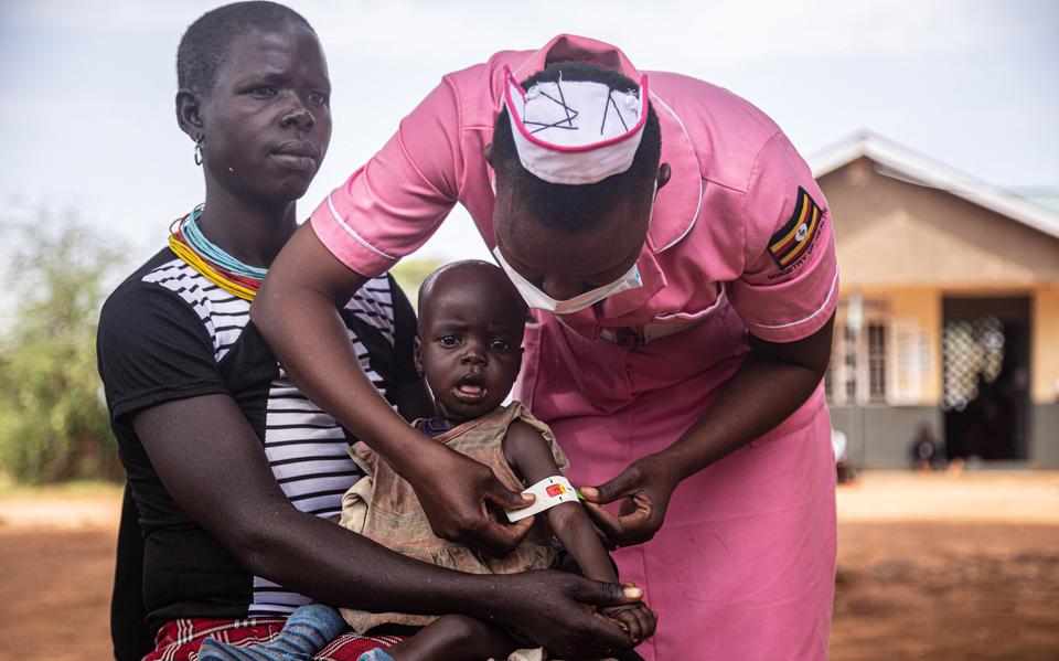 Een verpleegkundige onderzoekt een zwaar ondervoed kind in Nadunget, Oeganda. 