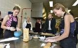 Onderwijsminister Dennis Wiersma bekijkt hoe leerlingen Annelyn Bos (links) en Nynke Galema Fryske dúmkes maken bij de Cooking Class. 