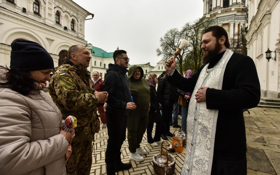 Een Oekraïense priester zegent gelovigen die een mandje met eieren bij zich hebben.